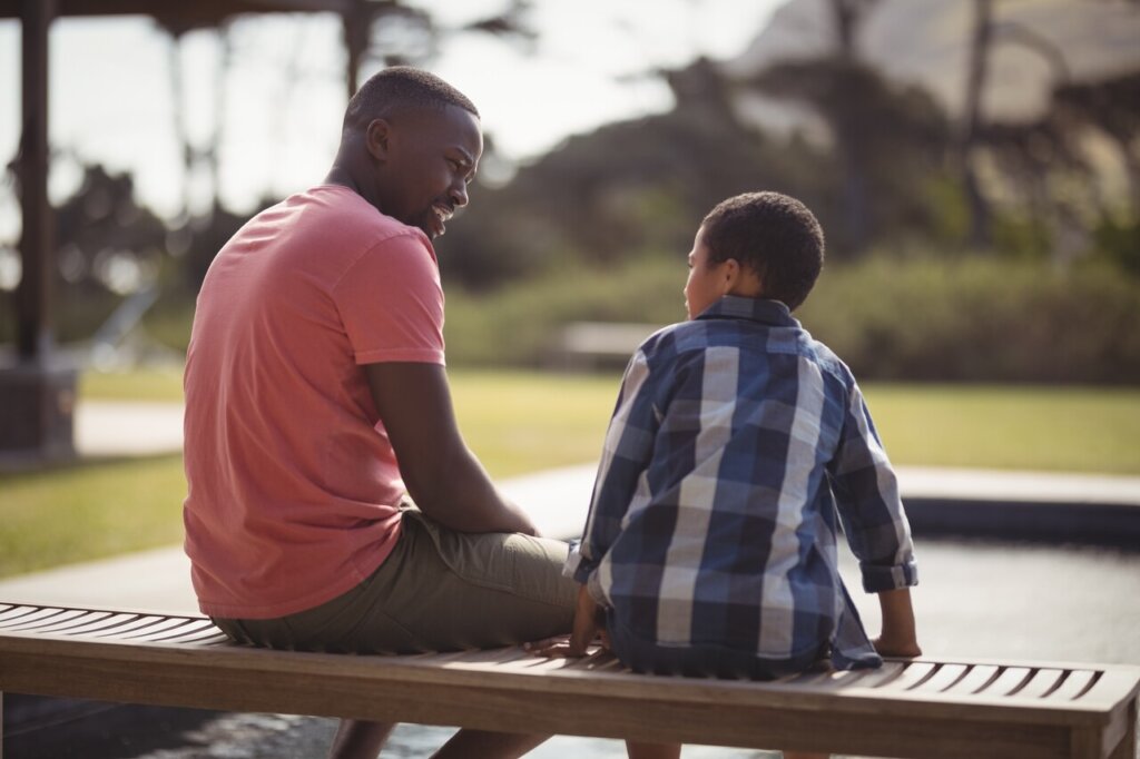 photo of father and son talking on a bench